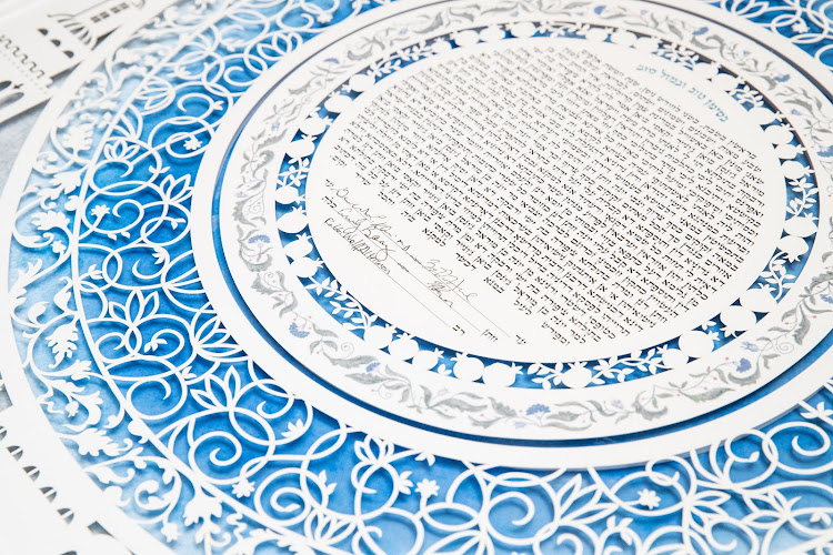 A hand holding a Ketubah, appreciating the artistry and meaning it holds.